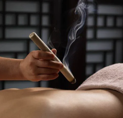 A moxa stick held above the back for warming care